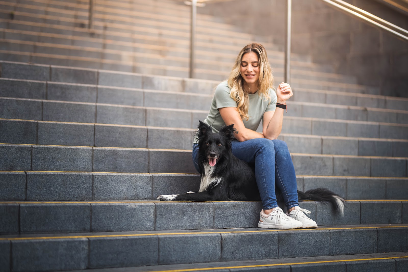 Roni sitting on a staircase with her dog resting beside her